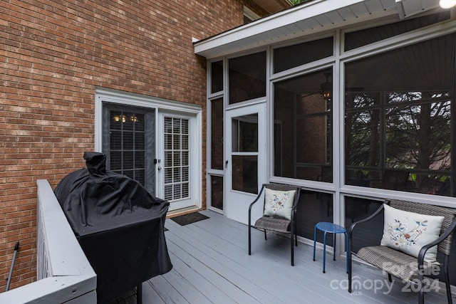 wooden terrace featuring a grill and a sunroom