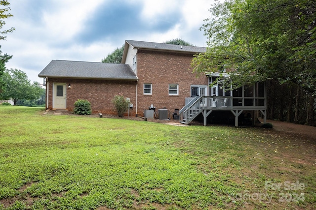 rear view of house featuring a sunroom, a yard, central AC, and a deck