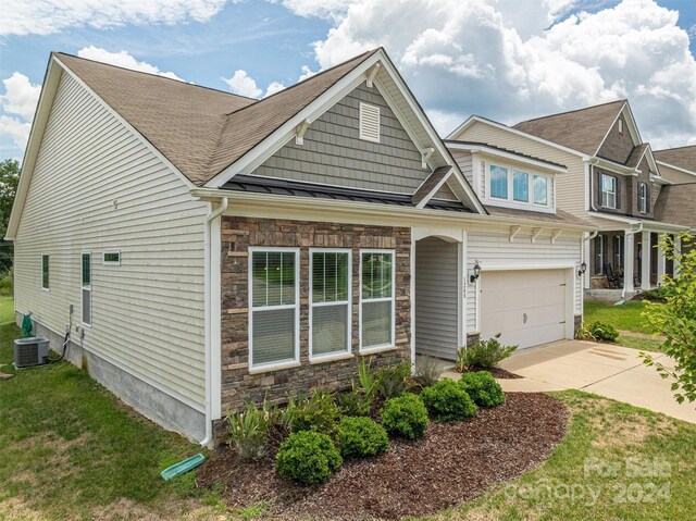 craftsman-style house with a garage, central air condition unit, and a front lawn