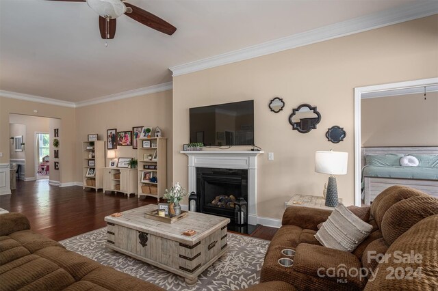 living room with ornamental molding, ceiling fan, and dark hardwood / wood-style floors