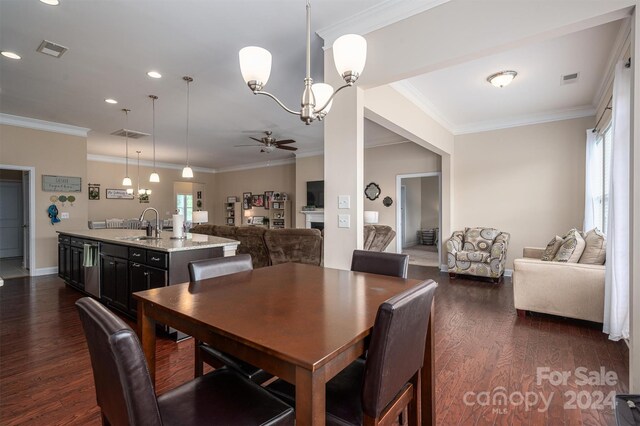 dining room with dark hardwood / wood-style floors, ceiling fan with notable chandelier, crown molding, and sink