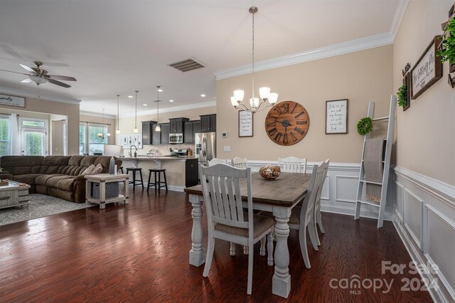 dining room featuring sink, ceiling fan with notable chandelier, dark hardwood / wood-style flooring, and ornamental molding