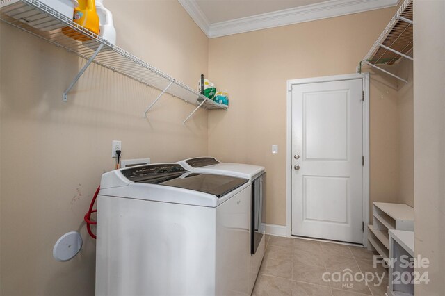 clothes washing area featuring light tile patterned flooring, crown molding, and washer and clothes dryer