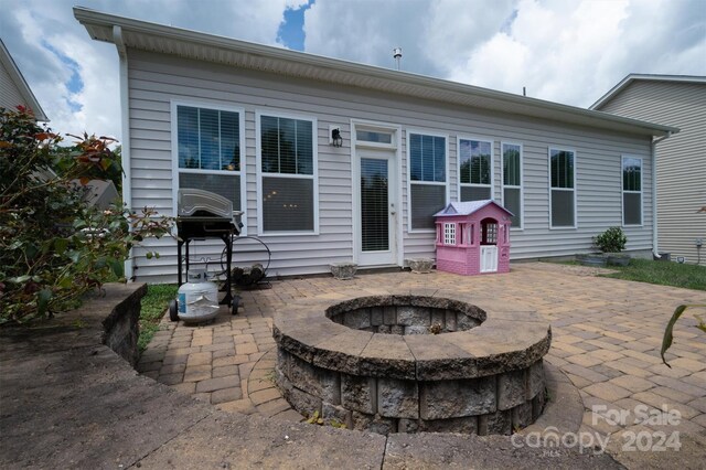 rear view of property featuring a patio area and a fire pit