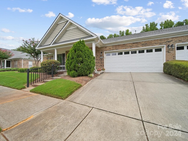 view of front of house featuring a garage, a front lawn, and covered porch