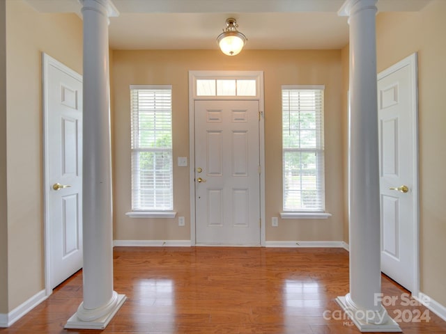 foyer with ornate columns, wood-type flooring, and a healthy amount of sunlight