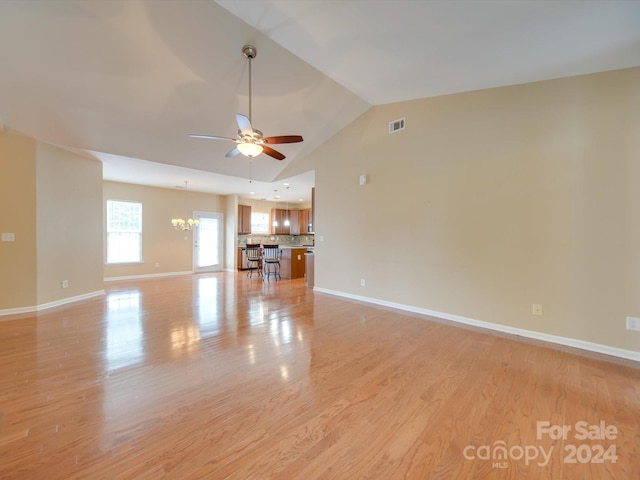 unfurnished living room featuring ceiling fan with notable chandelier, lofted ceiling, and light hardwood / wood-style floors