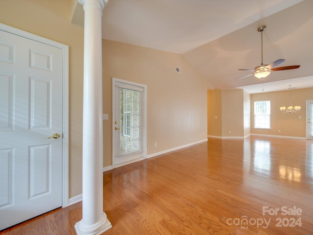 spare room featuring ornate columns, ceiling fan with notable chandelier, lofted ceiling, and light hardwood / wood-style floors