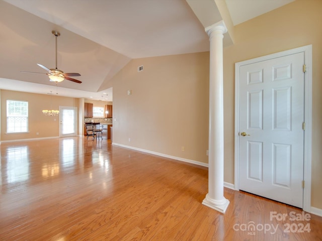 unfurnished living room with vaulted ceiling, decorative columns, ceiling fan with notable chandelier, and light wood-type flooring