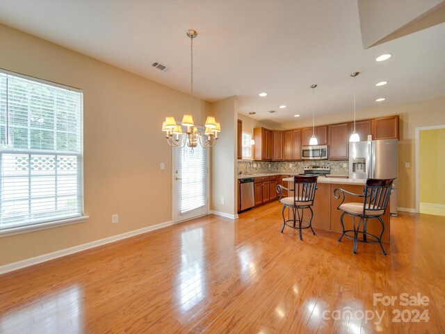 kitchen with light hardwood / wood-style floors, a wealth of natural light, decorative backsplash, and stainless steel appliances