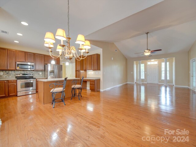 kitchen with stainless steel appliances, vaulted ceiling, hanging light fixtures, light hardwood / wood-style floors, and a center island