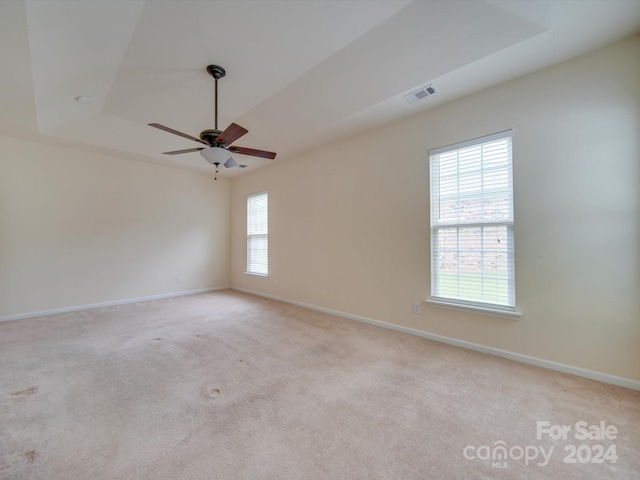 carpeted spare room featuring ceiling fan and a tray ceiling