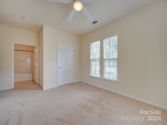 unfurnished bedroom with light carpet, ensuite bath, and ceiling fan