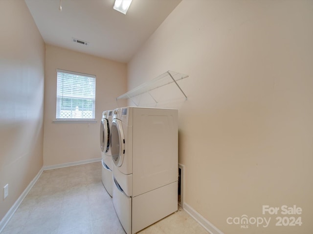 laundry room with washer and clothes dryer and light tile patterned floors