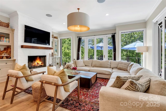 living room with a brick fireplace, ornamental molding, and light hardwood / wood-style flooring