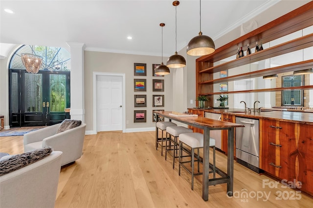 kitchen with light hardwood / wood-style floors, a kitchen breakfast bar, dishwasher, pendant lighting, and crown molding