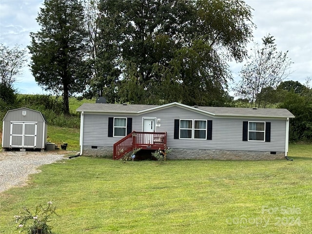 manufactured / mobile home featuring a front lawn and a storage unit