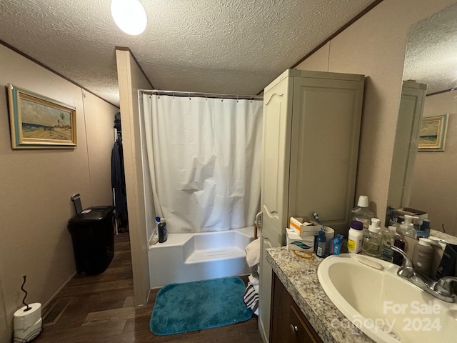 bathroom with a textured ceiling, vanity, wood-type flooring, and shower / bathtub combination with curtain