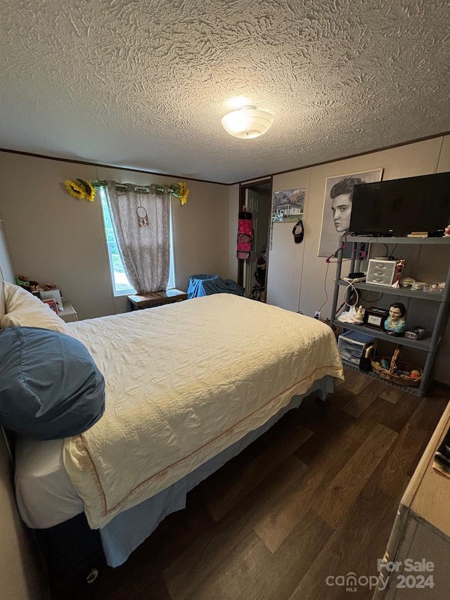 bedroom with a textured ceiling, a closet, and dark hardwood / wood-style flooring