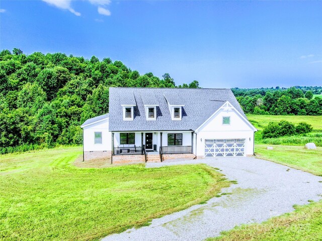 cape cod home featuring a front yard, covered porch, and a garage