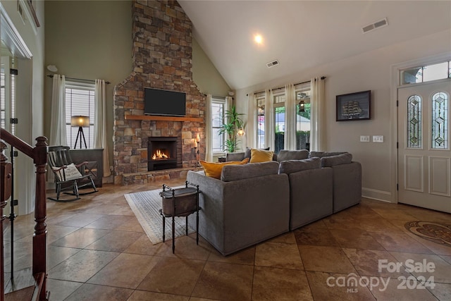 tiled living room with a stone fireplace and high vaulted ceiling