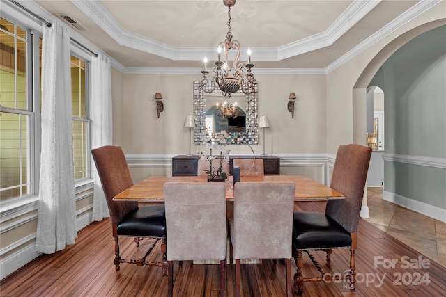 dining room featuring crown molding, a notable chandelier, a tray ceiling, and wood-type flooring