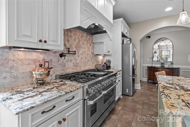 kitchen with white cabinetry, light stone countertops, custom exhaust hood, and stainless steel appliances