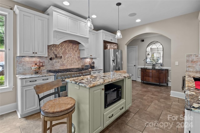 kitchen featuring white cabinetry, light stone countertops, a center island, and appliances with stainless steel finishes