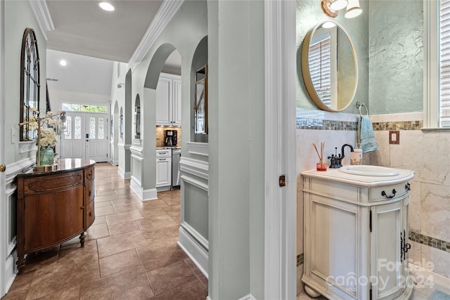 bathroom featuring vanity, ornamental molding, and tile walls