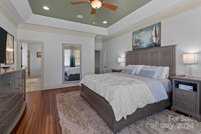 bedroom featuring crown molding, ceiling fan, dark hardwood / wood-style floors, connected bathroom, and a raised ceiling