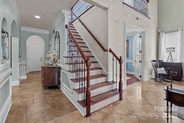 stairway featuring a high ceiling and ornamental molding