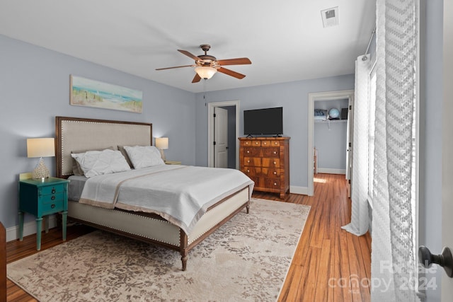 bedroom with a spacious closet, light hardwood / wood-style floors, and ceiling fan