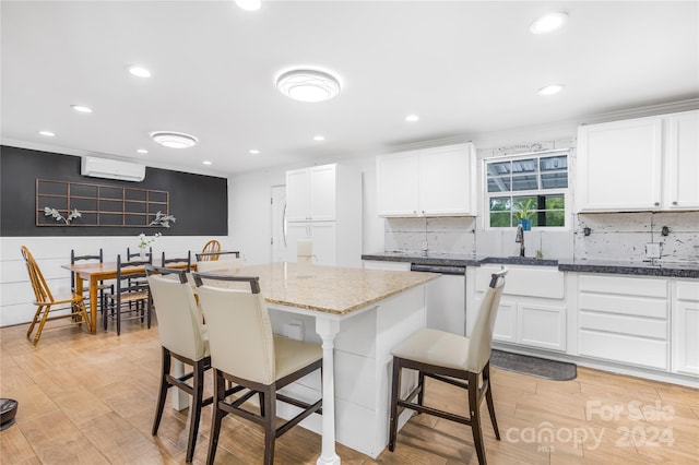 kitchen with sink, dishwasher, a center island, a wall mounted air conditioner, and white cabinets