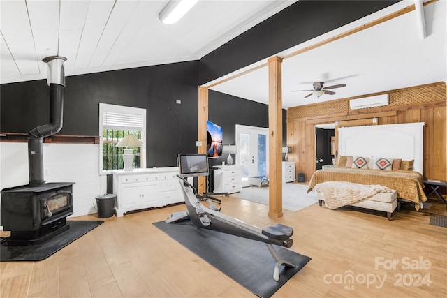 exercise area with crown molding, a wood stove, ceiling fan, and light hardwood / wood-style flooring