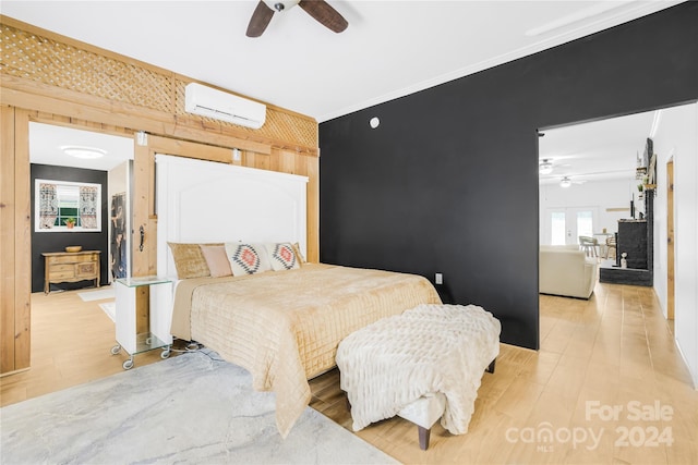 bedroom featuring light hardwood / wood-style flooring, a wall unit AC, and ceiling fan