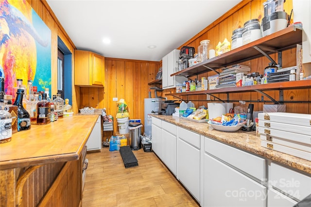 kitchen featuring white cabinetry and wood walls