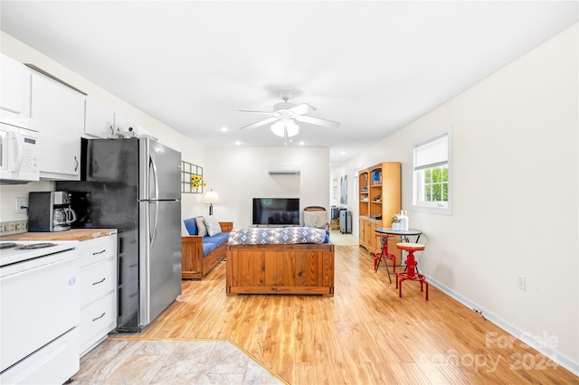 kitchen featuring white cabinetry, a wall mounted AC, ceiling fan, and white appliances