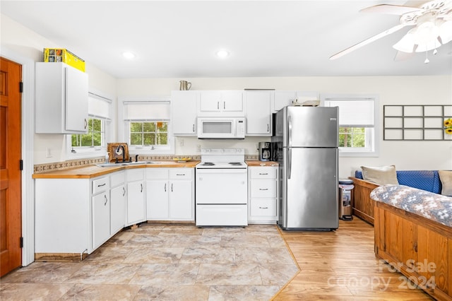 kitchen with white cabinetry, sink, white appliances, and a healthy amount of sunlight