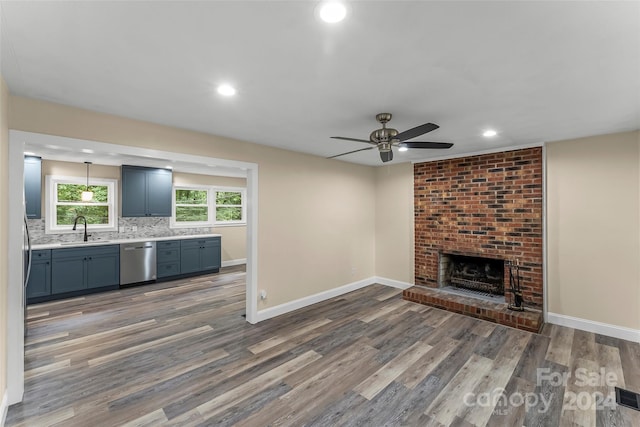 unfurnished living room featuring dark hardwood / wood-style flooring, sink, ceiling fan, and a fireplace