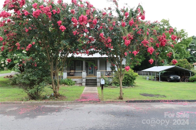 view of front of home featuring a carport, a porch, and a front yard