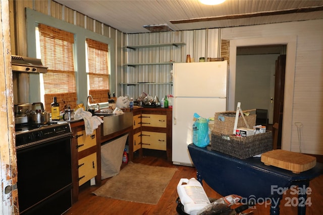 interior space featuring dark hardwood / wood-style floors, stove, sink, and white fridge