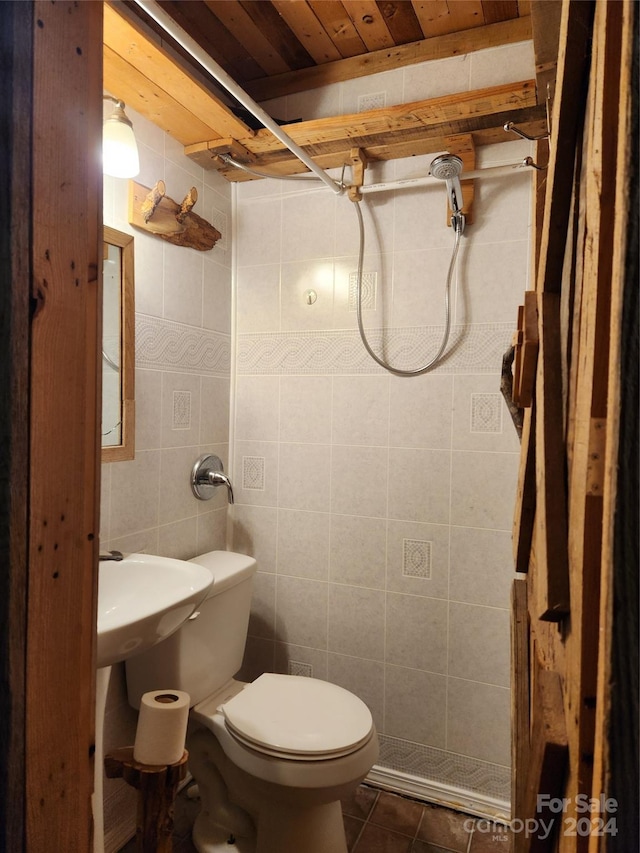 bathroom featuring walk in shower, toilet, sink, tile walls, and tile patterned flooring