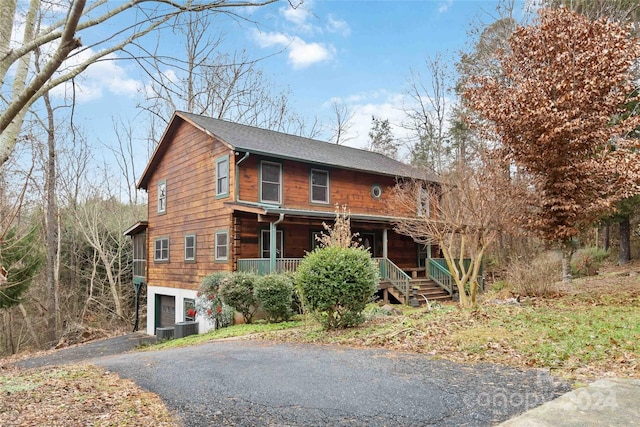 log cabin featuring central AC unit, a garage, and covered porch