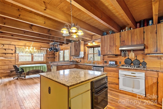 kitchen featuring wood walls, stainless steel appliances, a center island, and a notable chandelier