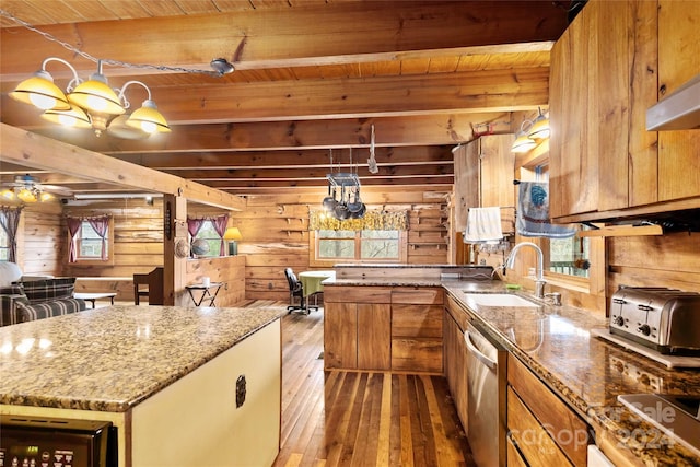 kitchen featuring sink, beam ceiling, wooden walls, and stainless steel dishwasher