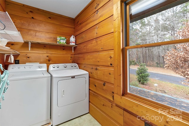 clothes washing area featuring washing machine and clothes dryer and wooden walls