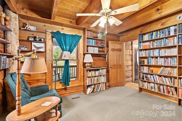 living area featuring wood ceiling, light carpet, wooden walls, ceiling fan, and beam ceiling