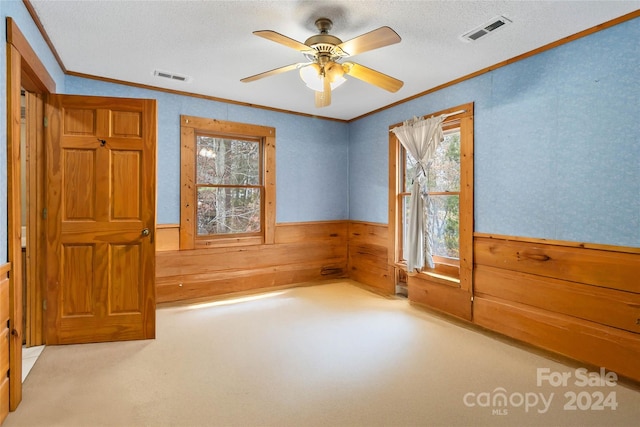 unfurnished bedroom featuring ornamental molding, light carpet, a textured ceiling, and wooden walls