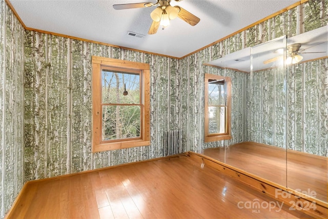 interior space featuring crown molding, hardwood / wood-style floors, ceiling fan, and a textured ceiling