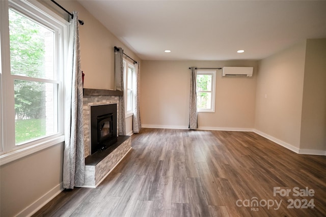 unfurnished living room featuring a wealth of natural light, dark hardwood / wood-style flooring, and an AC wall unit